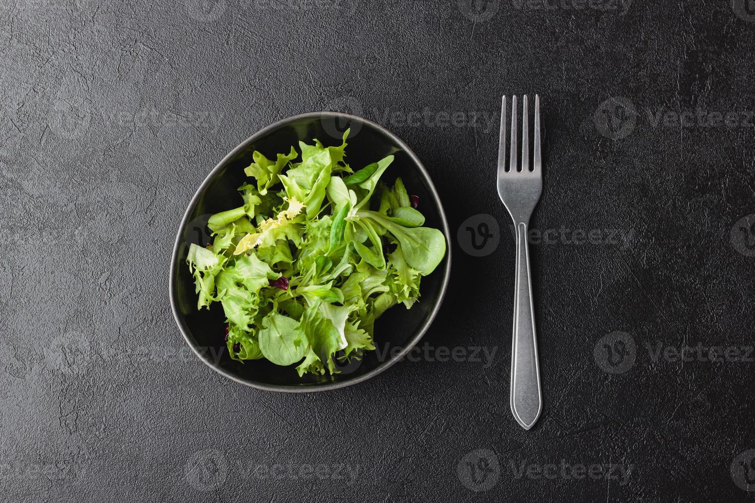 Green salad leaves in bowl on black table. photo