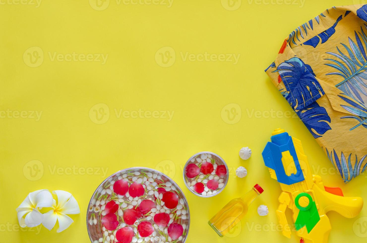 Songkran festival background with flowers and scented water to give blessing and accessories to play water on yellow background. photo