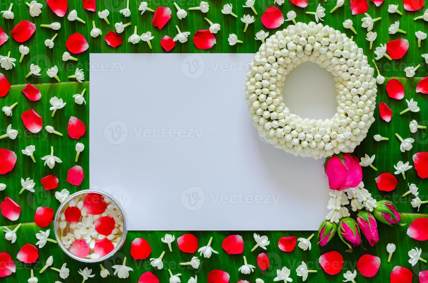 White blank paper with jasmine garland and flowers in water bowl on banana leaf background for Songkran festival. photo