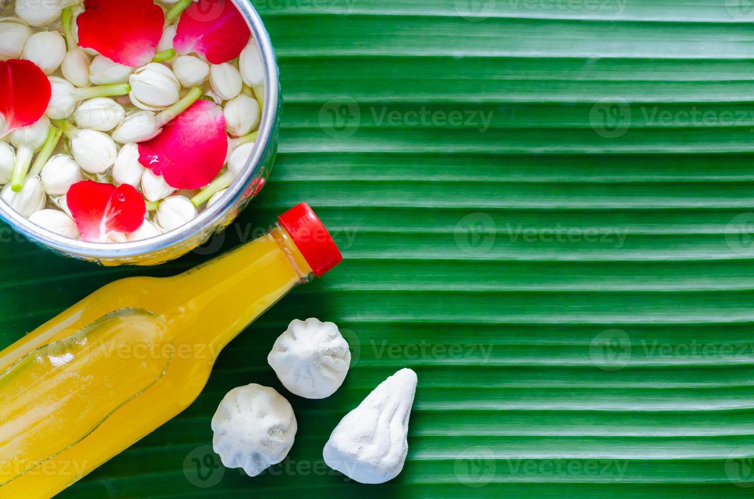 Songkran festival background with flowers in water bowl, scented water and marly limestone for blessing on banana leaf background. photo