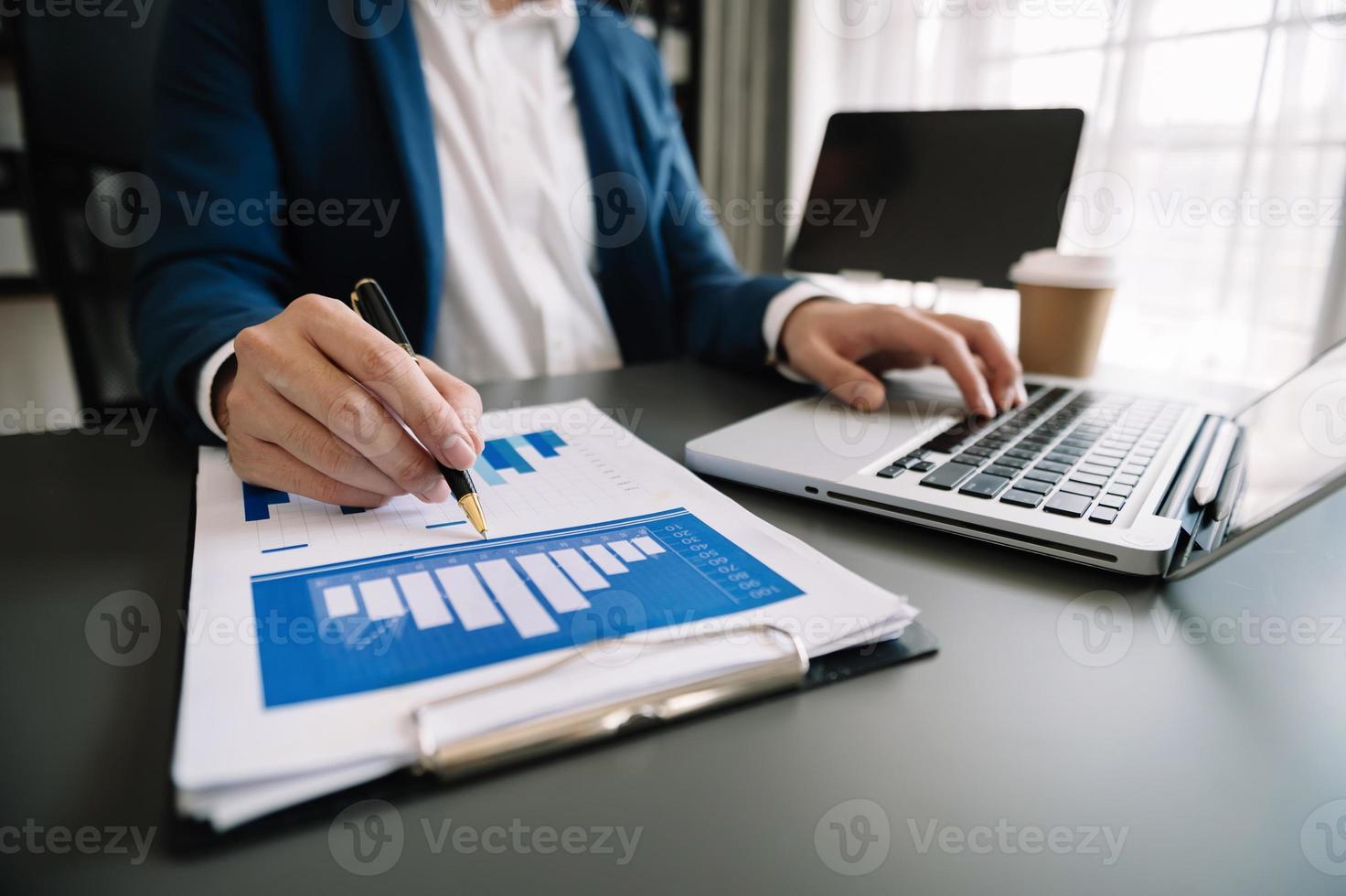 business documents on office table with smart phone and digital tablet and graph financial and woman working at office photo