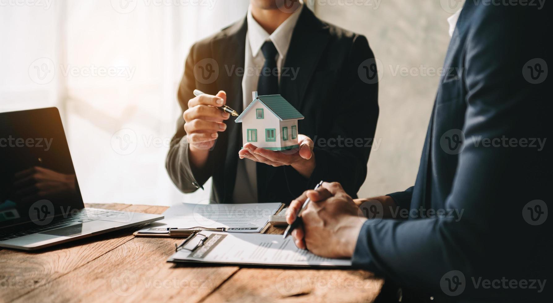 agente de bienes raíces que presenta y consulta al cliente para la toma de decisiones firmar un acuerdo de formulario de seguro, modelo de hogar, sobre la oferta de préstamo hipotecario en la oficina foto