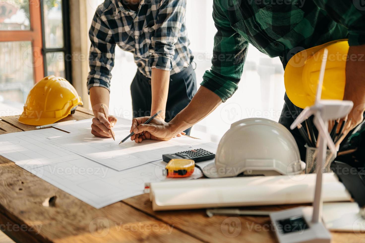 Two colleagues discussing data working and tablet, laptop with on on architectural project at construction site at desk in office photo