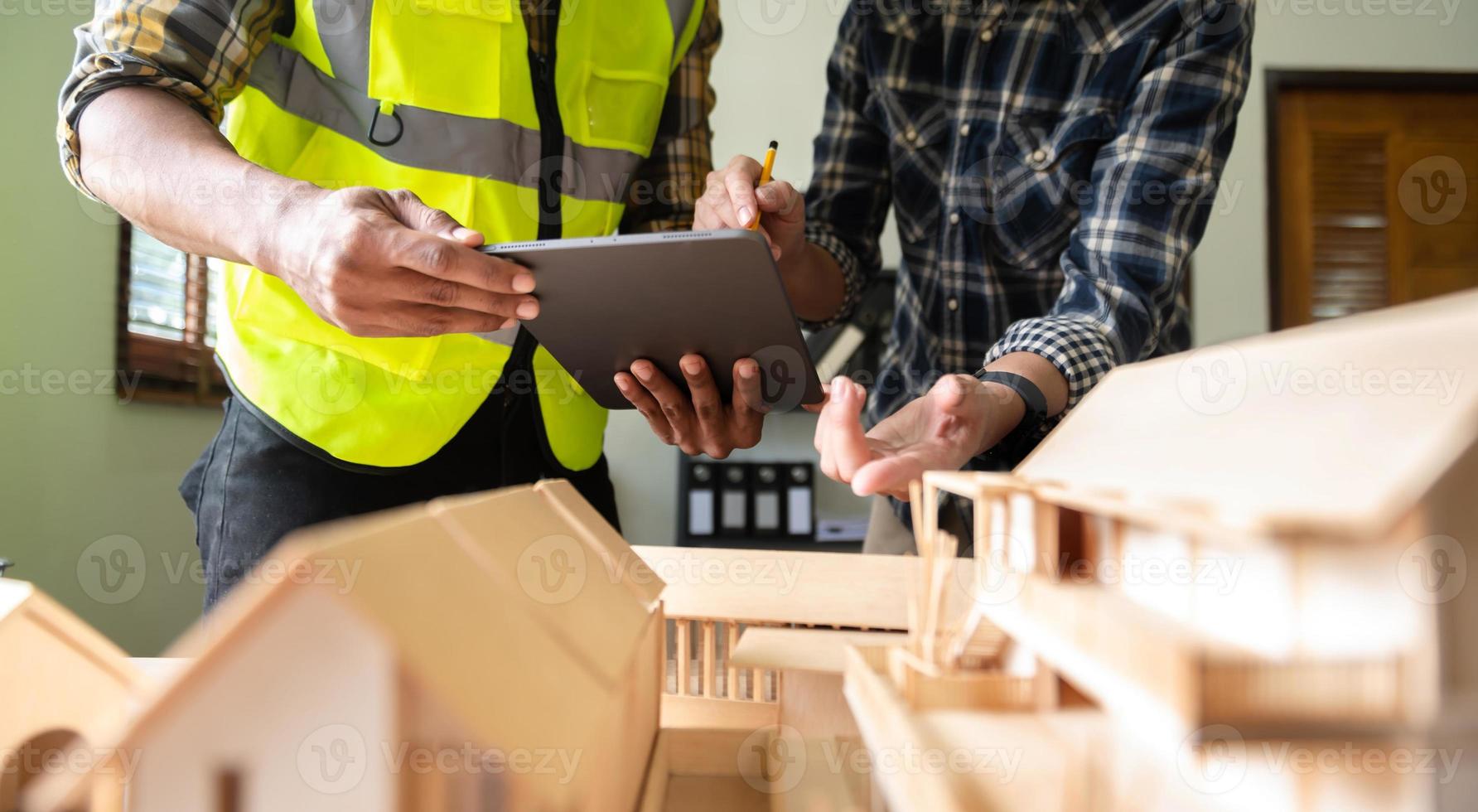 casa modelo a escala en la mesa con arquitectos. dos arquitectos haciendo modelo arquitectónico en la oficina juntos. para formar un nuevo edificio foto