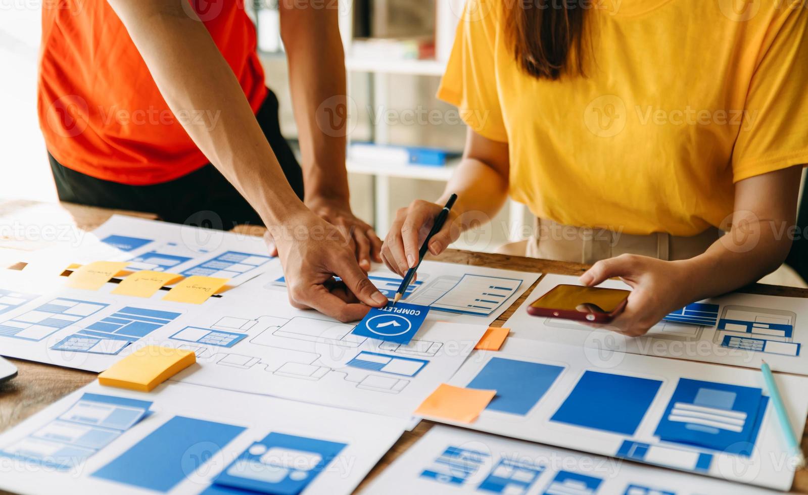 UX developer and ui designer brainstorming about mobile app interface wireframe design with customer breif and color code at modern office. photo