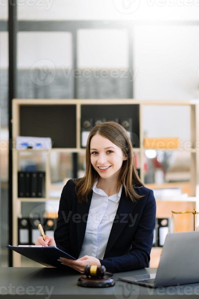 hermosa mujer abogada trabajando y mazo, tableta y computadora portátil en frente, consejo de justicia y concepto de ley foto