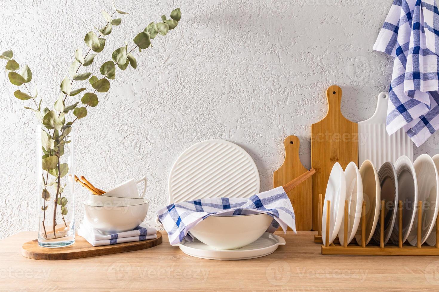 modern kitchen interior with various kitchen utensils on a wooden countertop. bowls, cutting wooden boards, plates. front view. clean house. photo