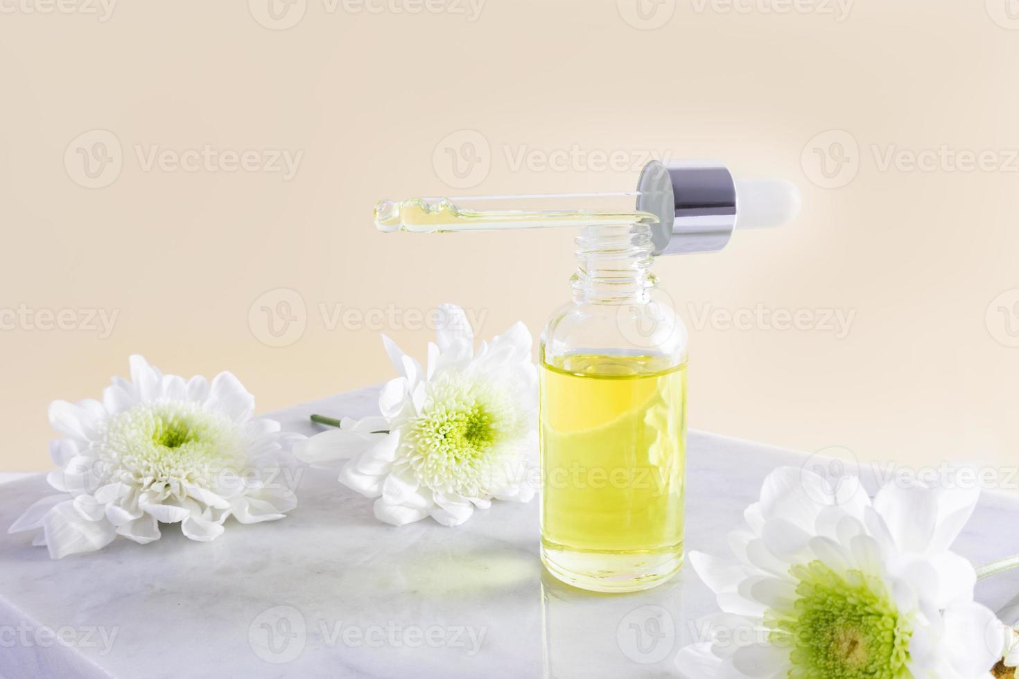 una botella cosmética abierta llena de una pipeta de aceite orgánico natural o suero para el cuidado facial y corporal. fondo beige. podio de mármol. foto