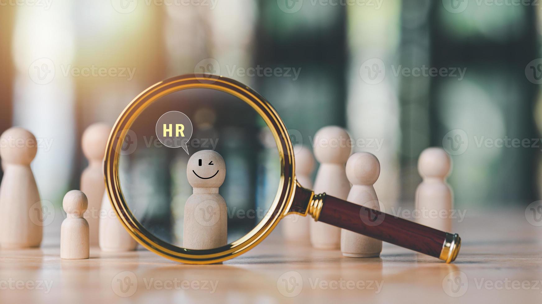 magnifying glass and wooden doll on table,HRM or Human Resource Management,strategic planning for success,developing people to be more efficient,choosing professional leaders based on their abilities photo