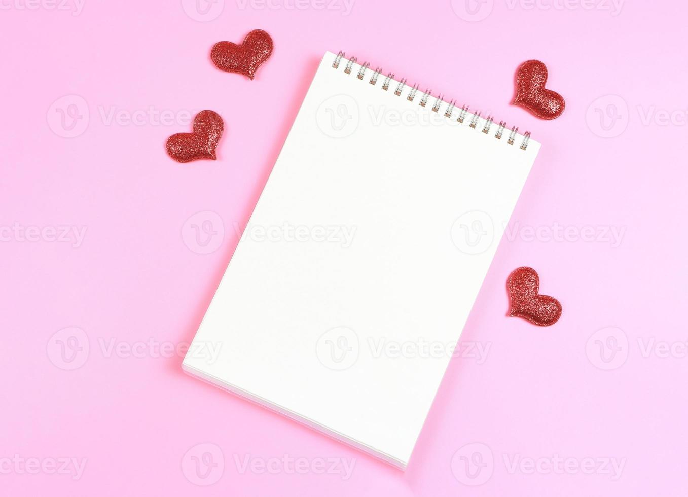 flat lay of opened  notebook with red glitter hearts on pink background with copy space. Love, Valentine's day, memory. photo
