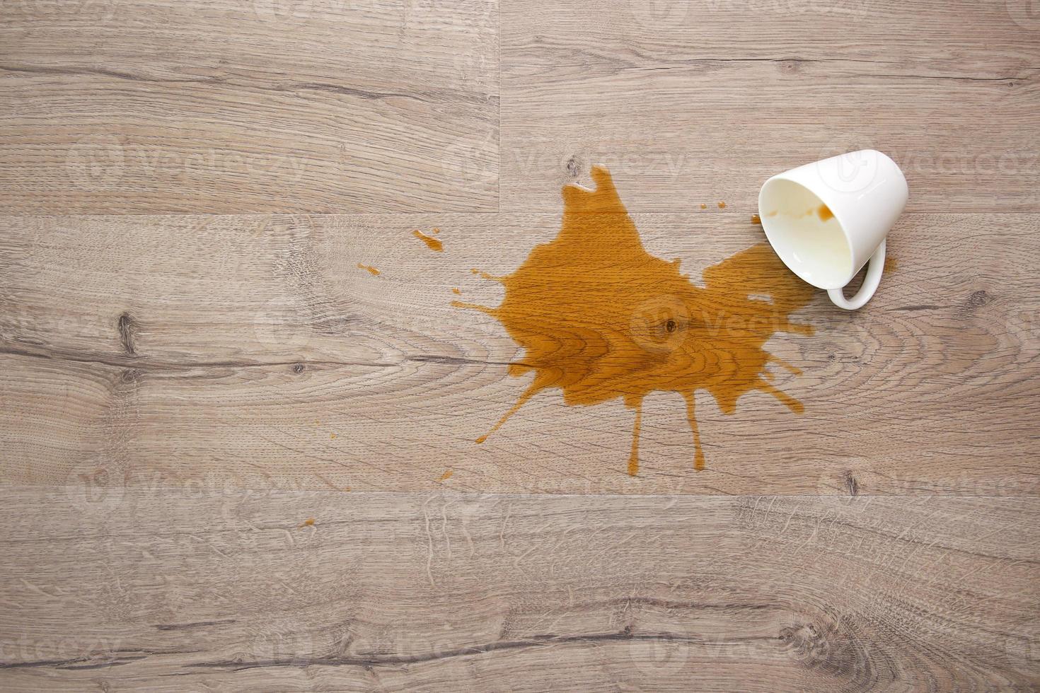 A cup of coffee fell on laminate, coffee spilled on floor. Focus on the puddle. Flat lay. Top view. photo