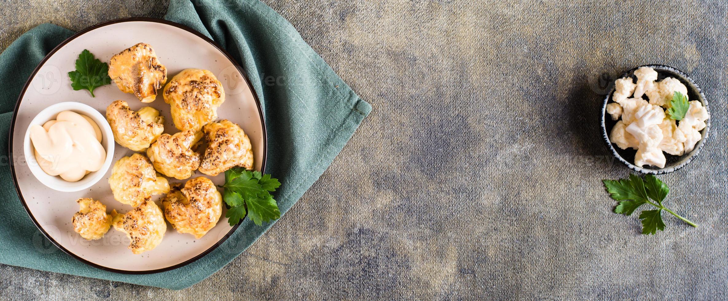 alitas de búfalo de coliflor vegetarianas y salsa en un plato sobre la mesa. vista superior. banner web foto