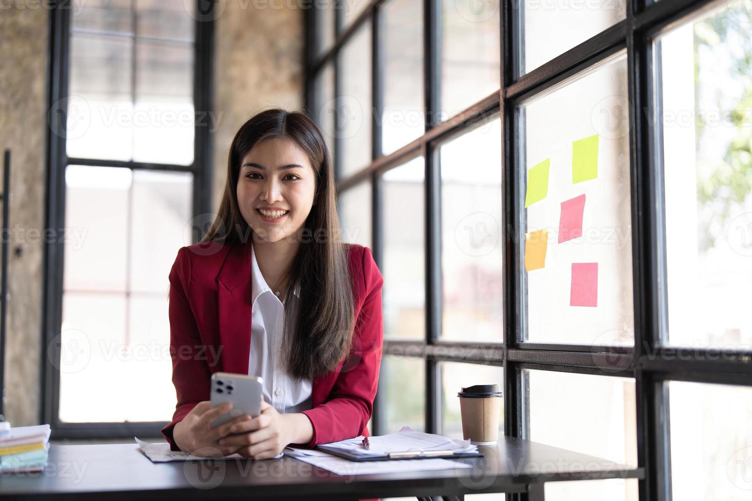 Young smiley attractive, businesswoman using sticky notes in glass wall to writing strategy business plan to development grow to success photo