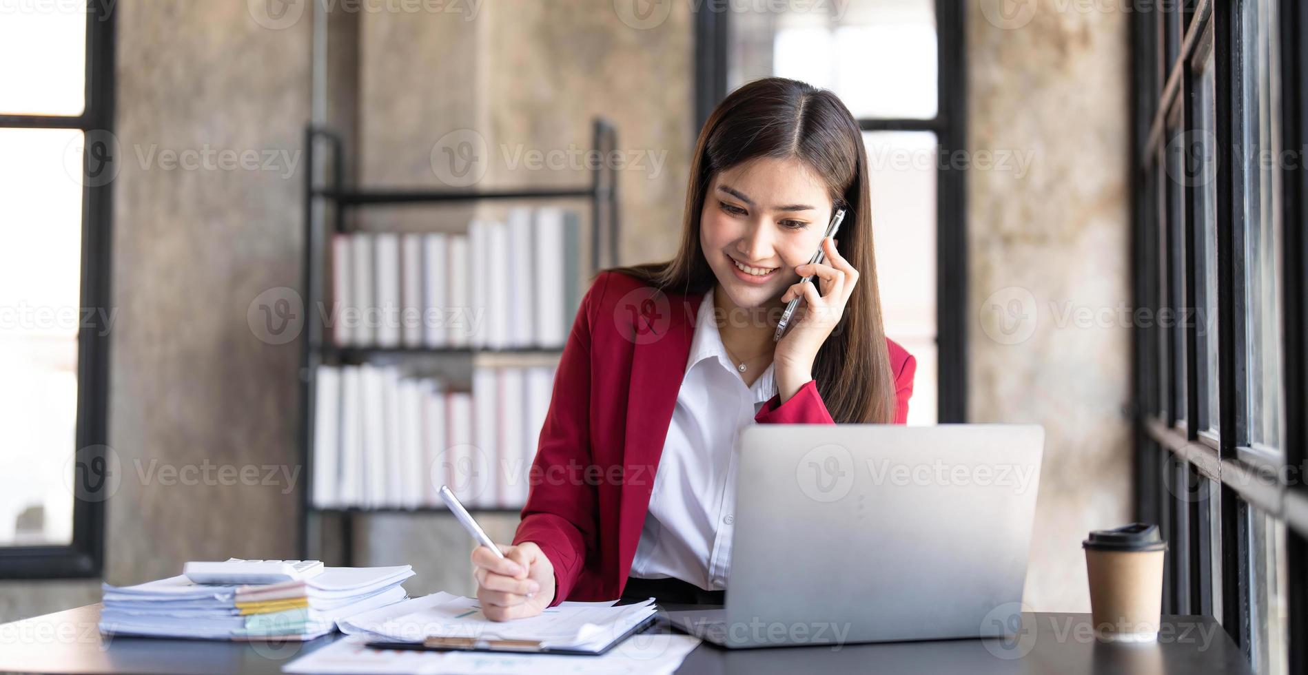 Portrait of a cheerful young business Asian woman using smartphone application in workplace office, concept of Small business employee freelance online sme marketing e-commerce telemarketing. photo