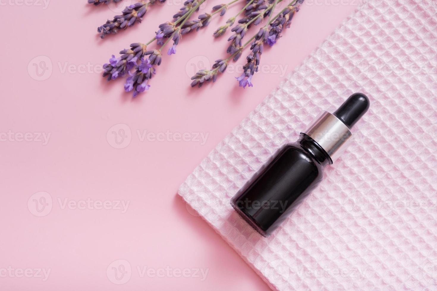 Cosmetic oil in pipette bottle with lavender flowers on colored background. Top view. Flat lay photo