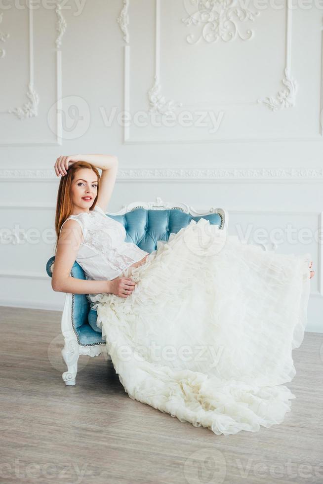 red-haired pregnant young girl in a blue armchair photo