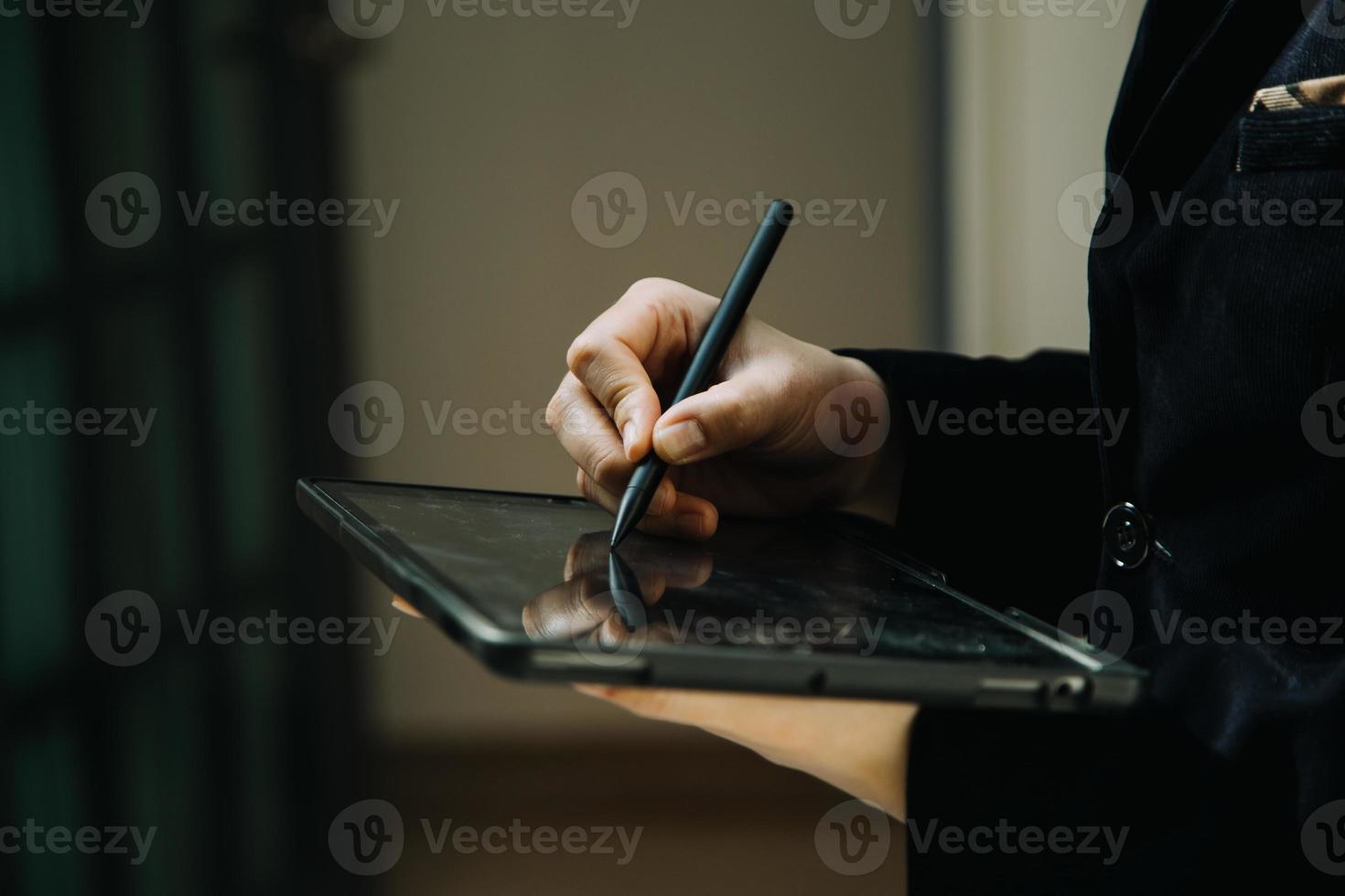 hombre de negocios maduro que usa una tableta digital para discutir información con un colega más joven en un moderno salón de negocios foto