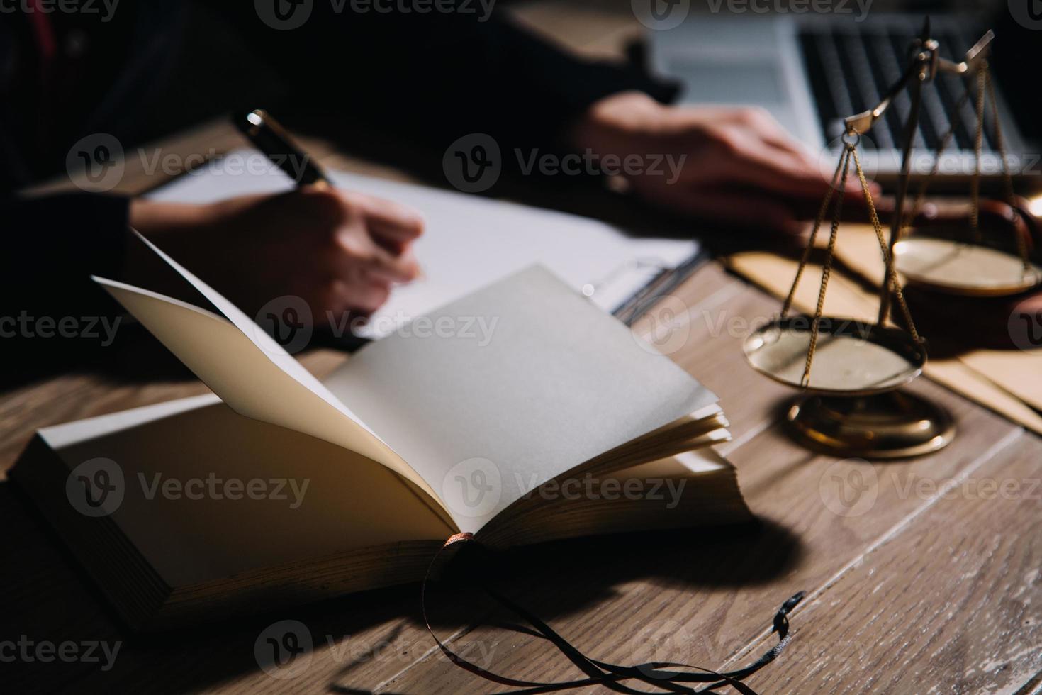 concepto de justicia y derecho. juez masculino en una sala de audiencias con el mazo, trabajando con computadora y teclado de acoplamiento, anteojos, en la mesa a la luz de la mañana foto