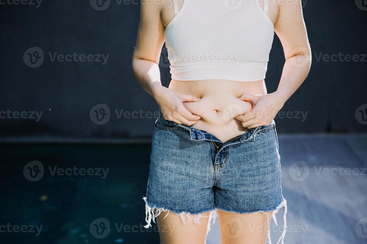 mujer gorda, barriga gorda, gordita, mujer obesa mano sosteniendo grasa abdominal excesiva con cinta métrica, concepto de estilo de vida de dieta de mujer foto