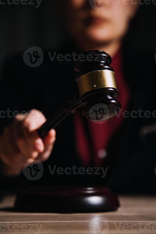 Justice and law concept.Male judge in a courtroom with the gavel, working with, computer and docking keyboard, eyeglasses, on table in morning light photo