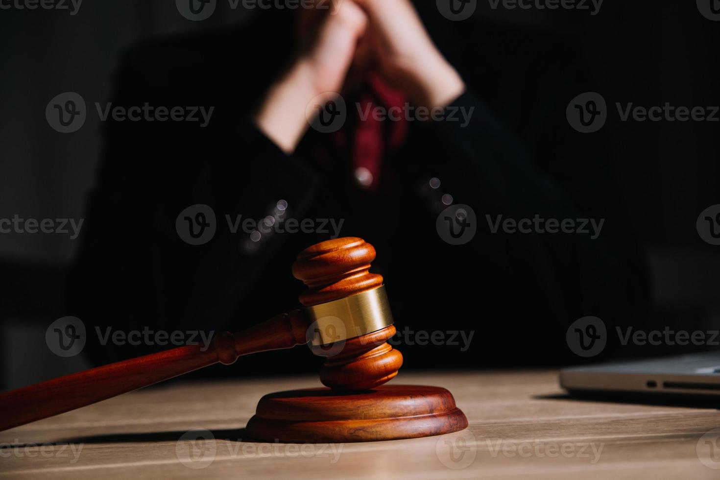 Justice and law concept.Male judge in a courtroom with the gavel, working with, computer and docking keyboard, eyeglasses, on table in morning light photo