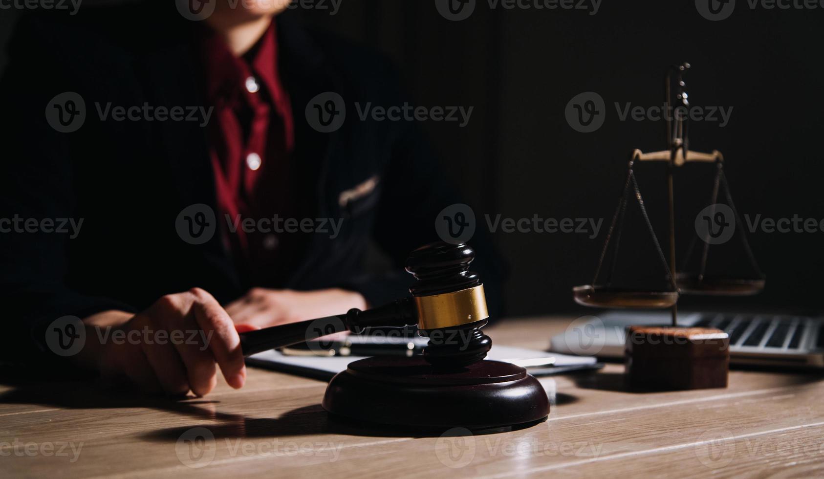 concepto de justicia y derecho. juez masculino en una sala de audiencias con el mazo, trabajando con computadora y teclado de acoplamiento, anteojos, en la mesa a la luz de la mañana foto