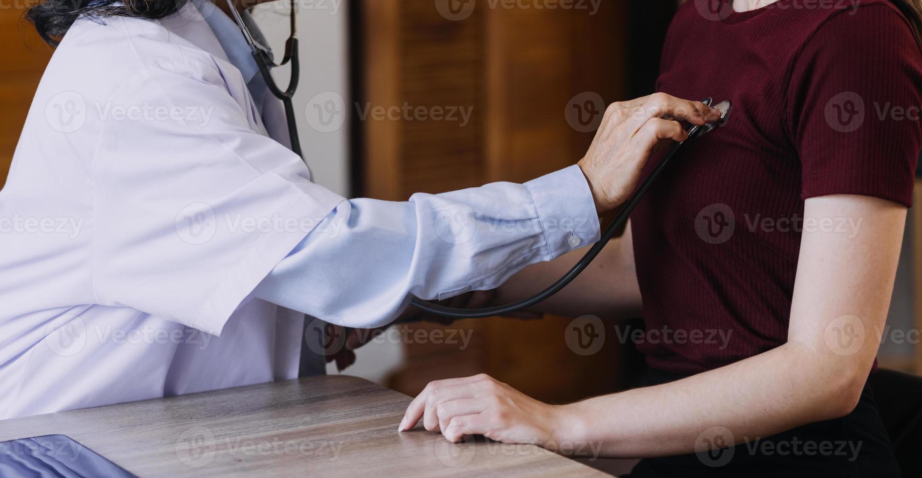 servicio de enfermería domiciliaria y cardiología asistencial a personas mayores. Primer plano de una joven doctora hispana enfermera comprobar los latidos del corazón de un hombre caucásico maduro usando un estetoscopio durante la visita foto