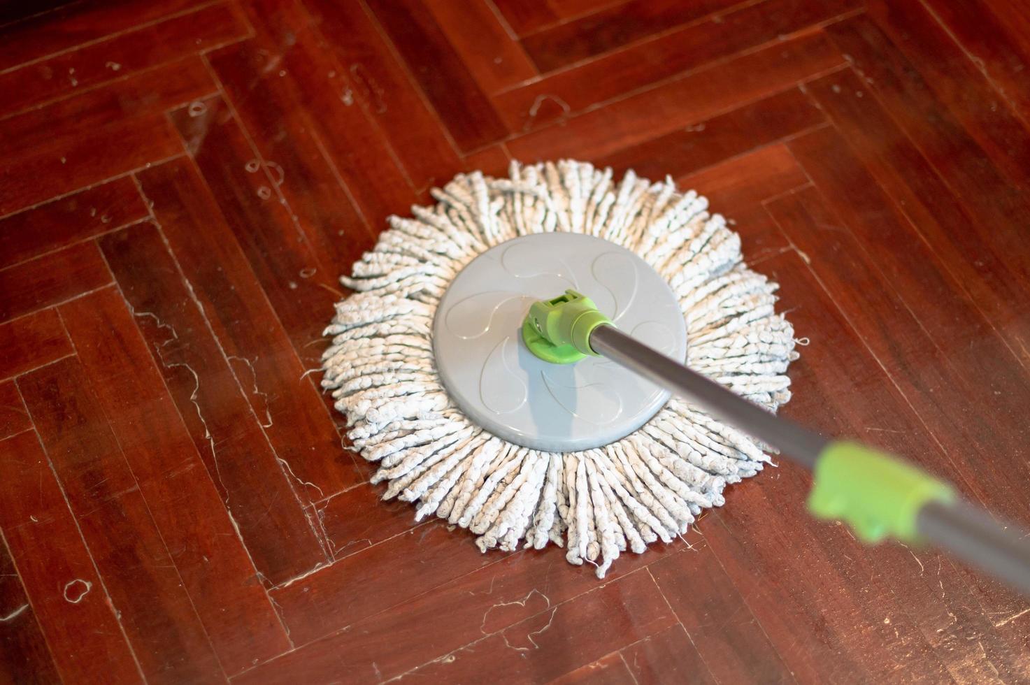 Female hand in protective gloves using a flat wet-mop while cleaning floor in the house. photo