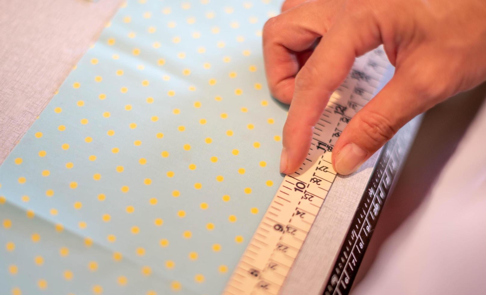 Female hands of designer at work with fabric close-up. Tailor measuring necessary amount of material for sewing cloth. photo