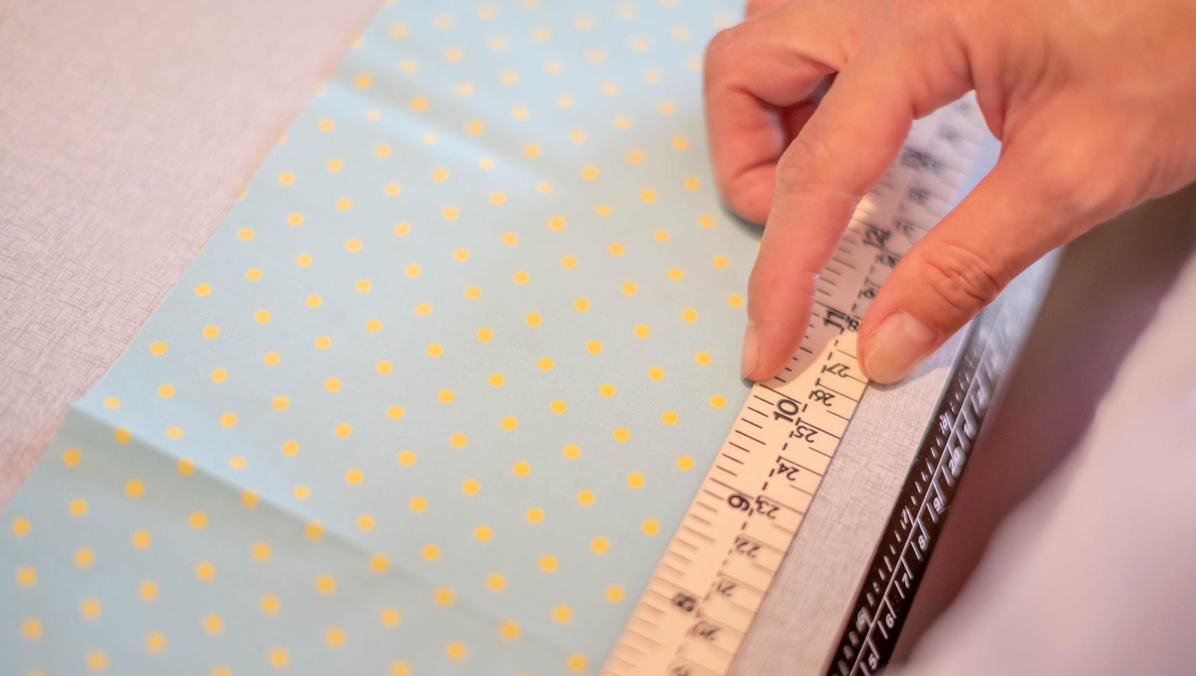 Female hands of designer at work with fabric close-up. Tailor measuring necessary amount of material for sewing cloth. photo