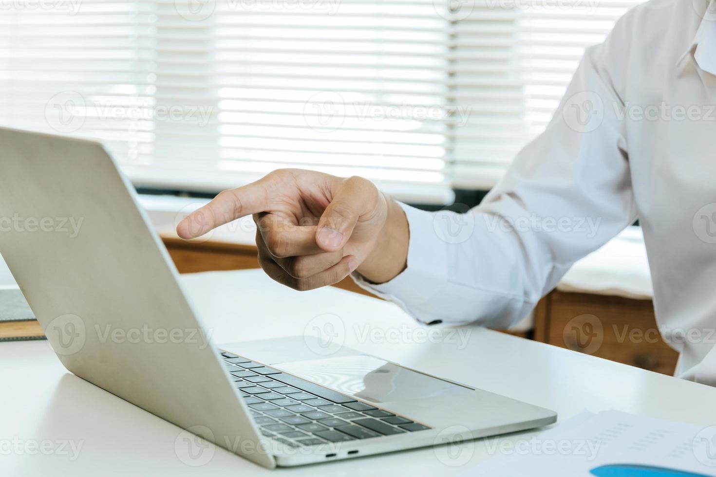 business man pointing hand working and calculating about finance document report and digital laptop computer on desk at home office, digital online marketing and financial business, technology concept photo