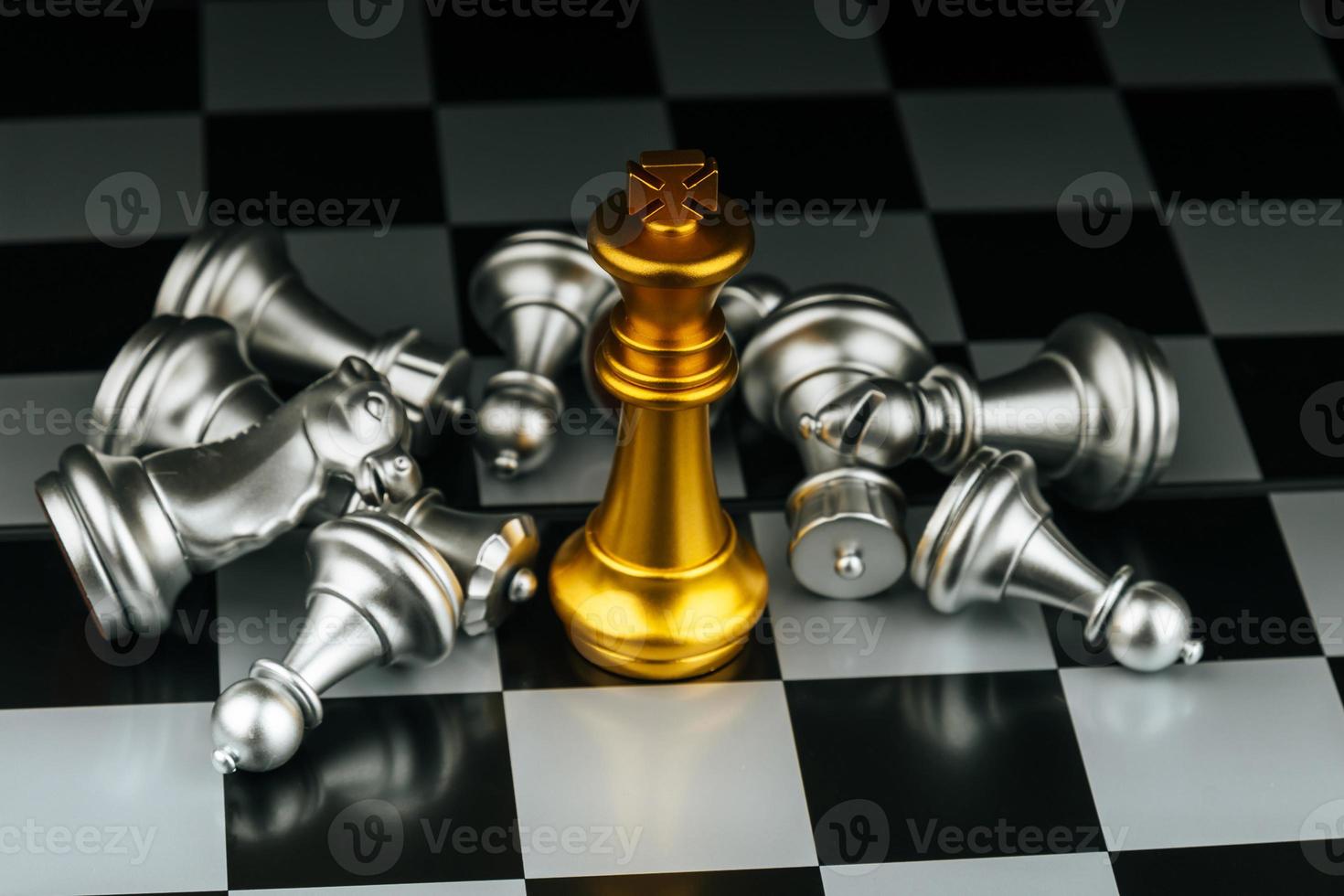 Winner. gold king surrounded with silver chess pieces on chess board game competition with copy space on dark background, chess battle, success, team leader, teamwork and business strategy concept photo