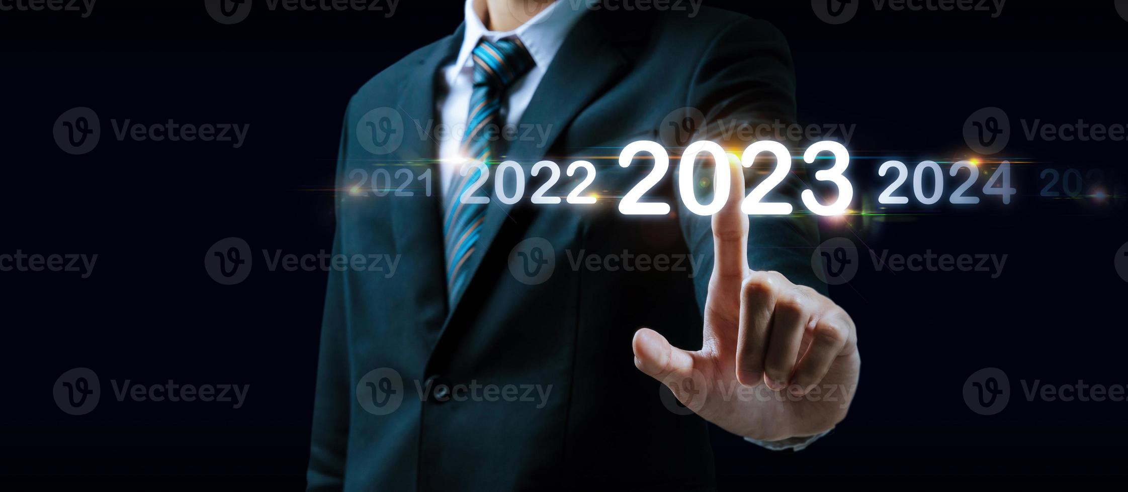 2023. mano de hombre de negocios tocando y señalando el año 2023 con pantalla virtual sobre fondo oscuro, meta, cambio de 2022 a 2023, estrategia, inversión, planificación empresarial, concepto de feliz año nuevo foto