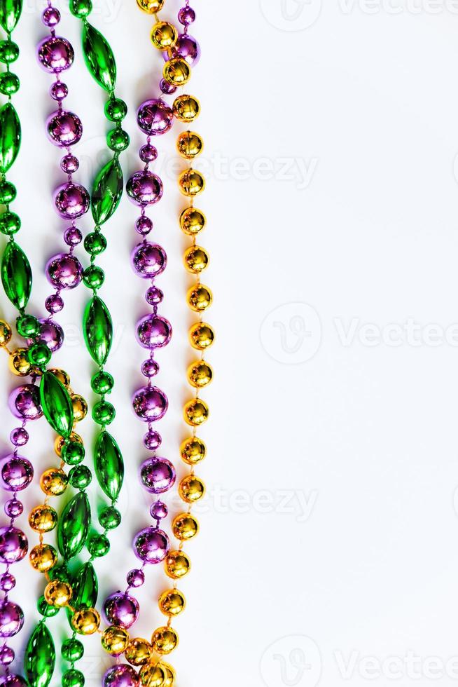 Mardi Gras background. Gold, green and purple beads on white background. Fat Tuesday symbol. photo