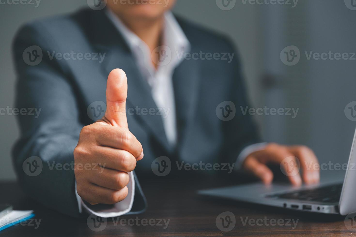 Close up of businesswoman showing raised thumbs at the camera as a gesture of recommendation or good choice. Professional support and service team demonstrates satisfaction and gives a positive. photo
