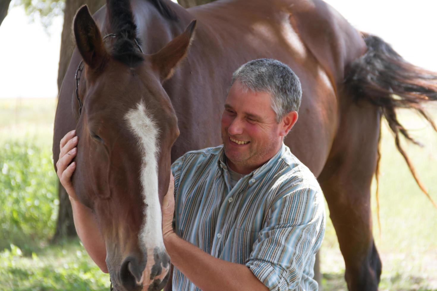 hombre sonriente con su caballo en el campo argentino foto