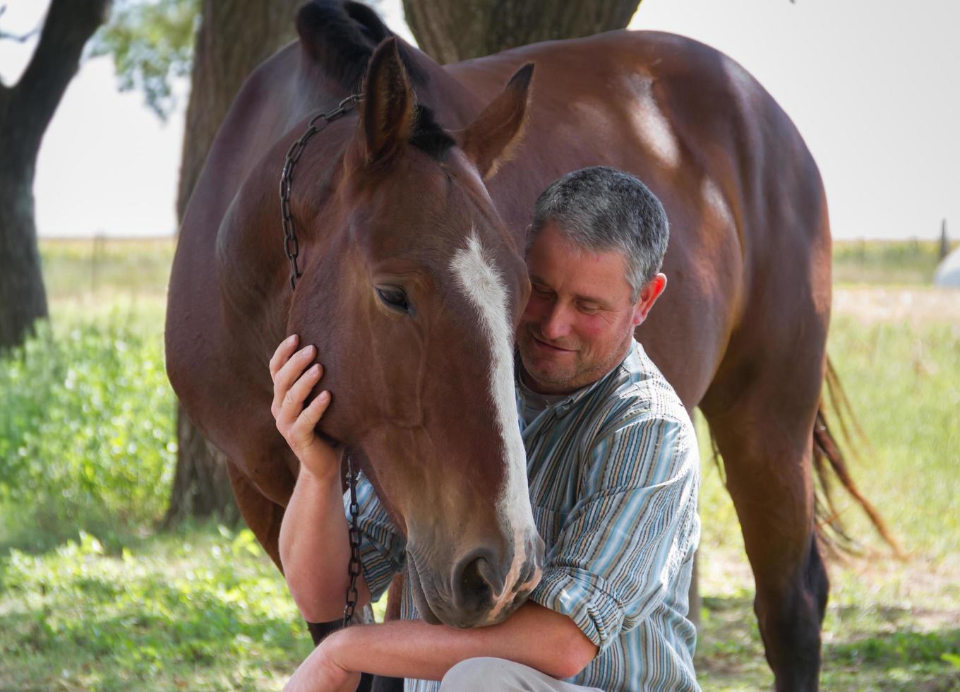 hombre sonriente con su caballo en el campo argentino foto