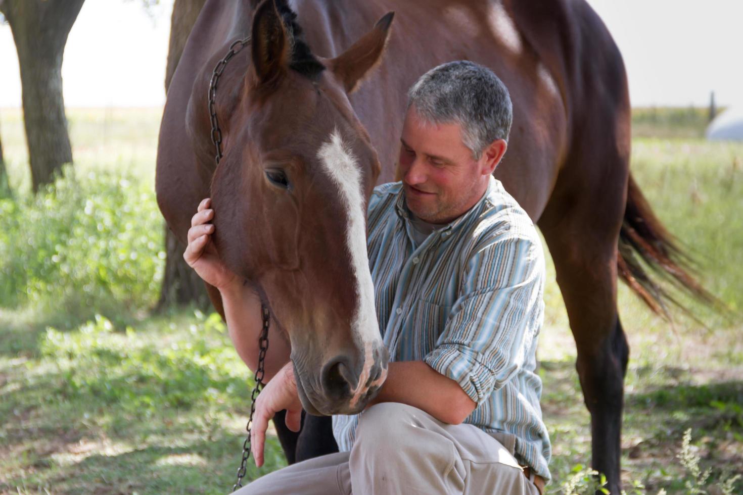 hombre sonriente con su caballo en el campo argentino foto