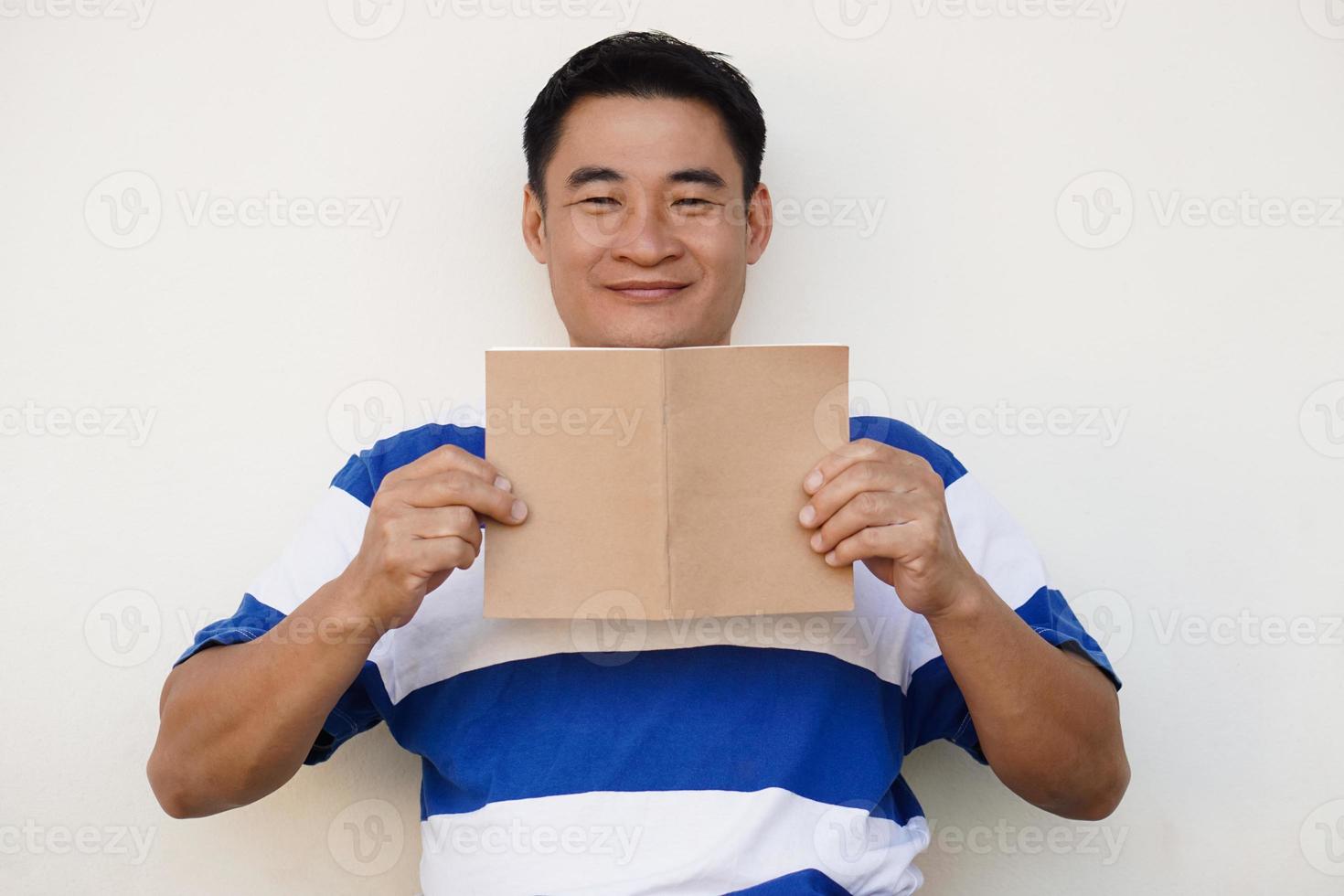Handsome Asian man holds book to read. Concept , Relax time, pastime, hobby. Give time for yourself to read books , magazine, novels. Reading in daily life. Education ,knowledge or  pleasure. photo