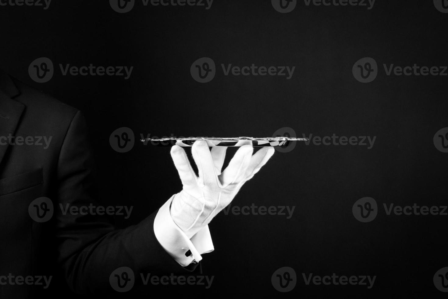 Isolated Image of White Gloved Hand Holding Silver Serving Tray on Black Background. Service Industry and Professional Hospitality. photo