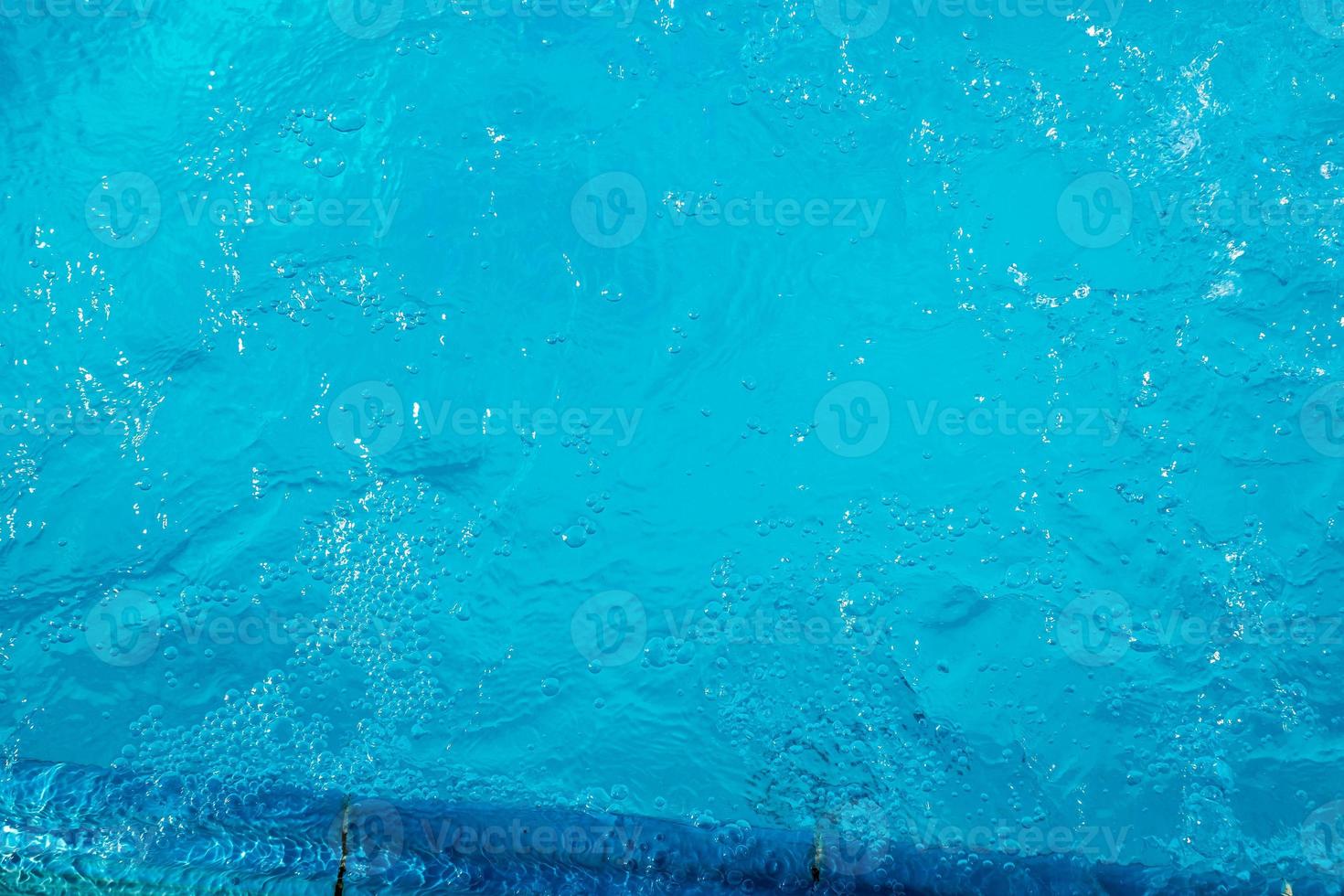 textura superficial de agua tranquila clara de color azul transparente borrosa con salpicaduras y burbujas. fondo de naturaleza abstracta de moda. ondas de agua a la luz del sol. fondo de agua foto