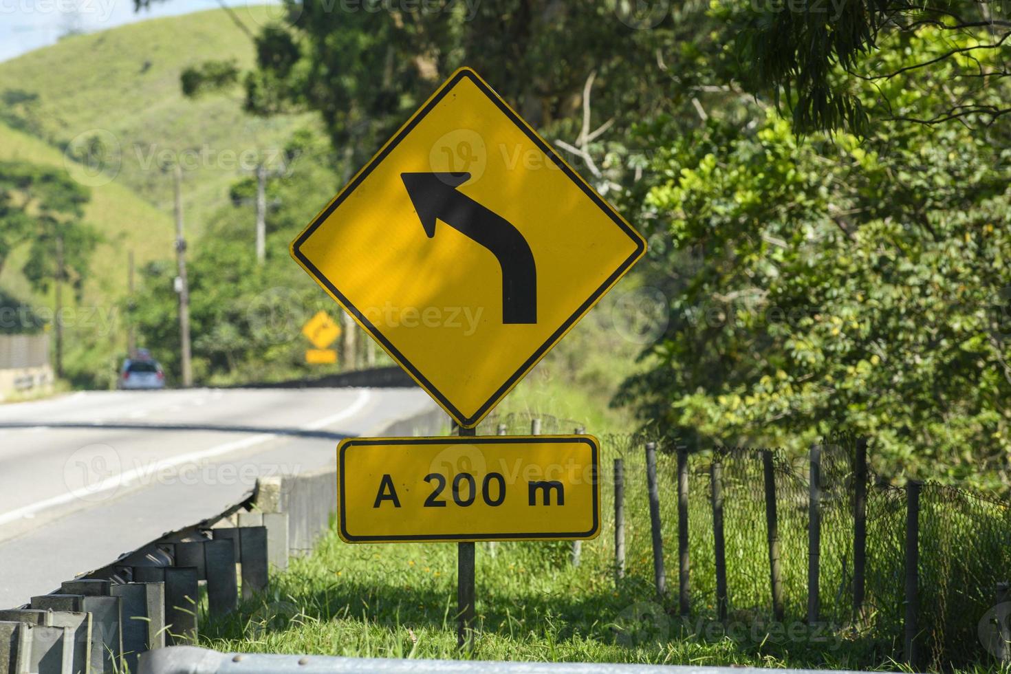 yellow road sign signaling a forward curve on a road photo