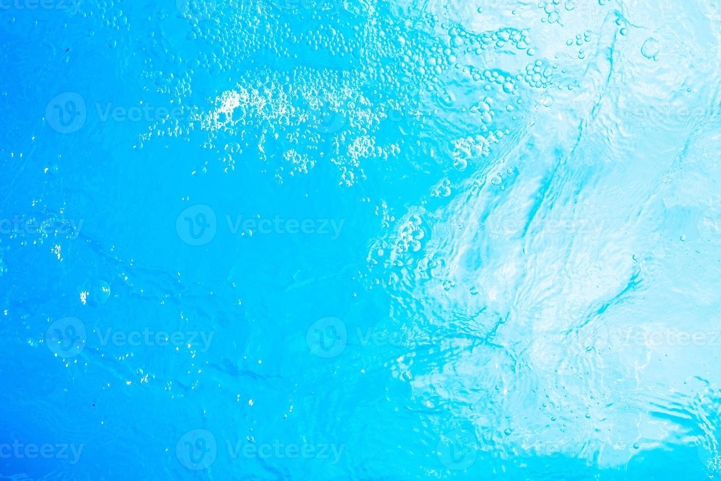Blurred transparent blue colored clear calm water surface texture with splashes and bubbles. Trendy abstract nature background. Water waves in sunlight. water background photo