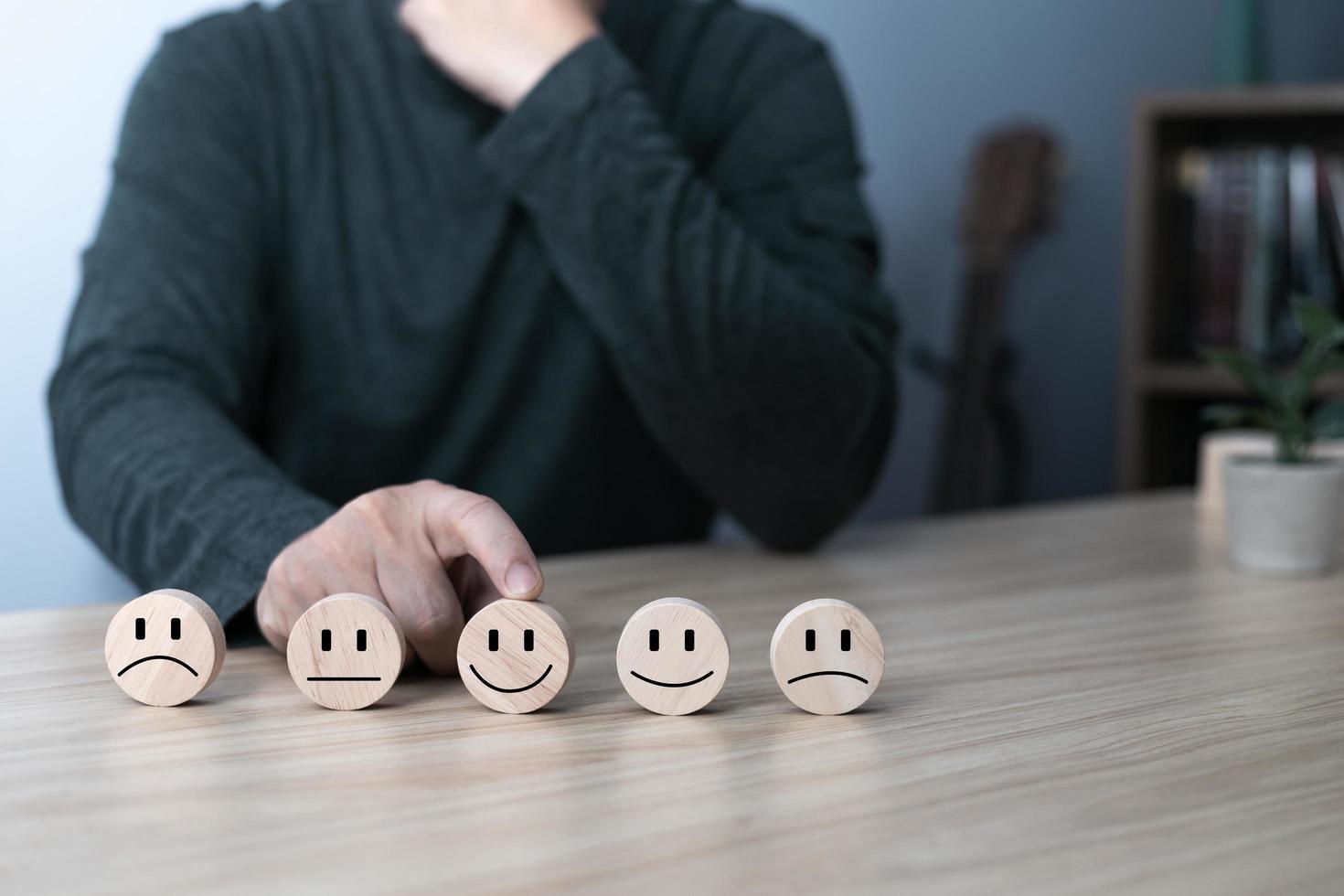 la mano de un hombre de negocios elige una cara sonriente en un círculo de bloques de madera.experiencia de servicio al cliente y encuesta de satisfacción empresarial.calificación muy impresionada.concepto de encuesta de satisfacción. foto