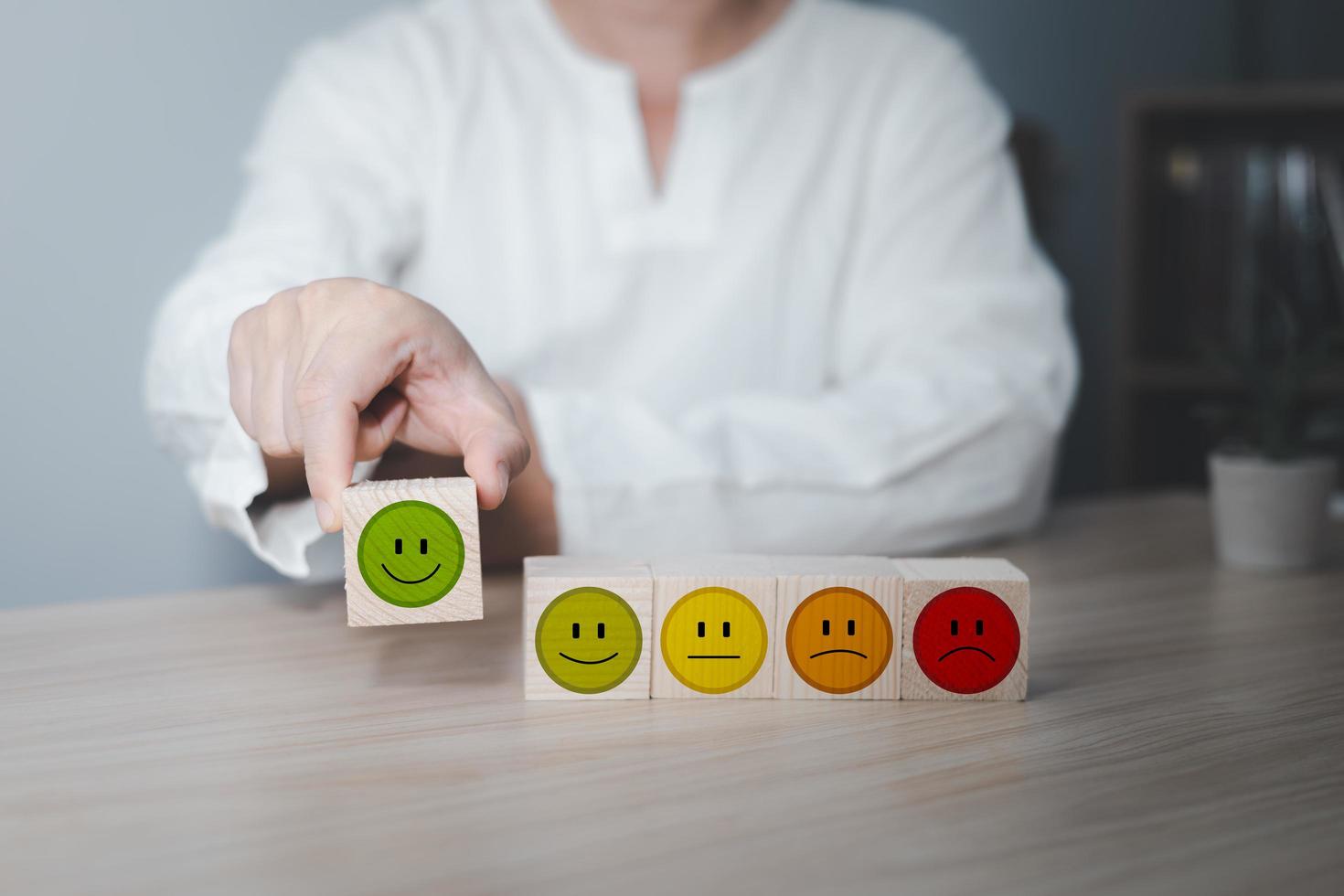 Hand of a businessman chooses a smile face on wood block circle.Customer service experience and business satisfaction survey.rating very impressed.Satisfaction survey concept. photo