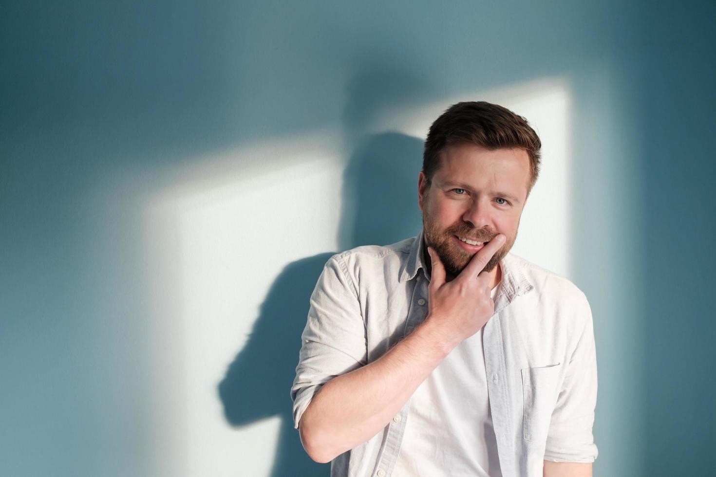 Mysterious man smiles leaning against the wall in the rays of sunlight. Copy space. photo