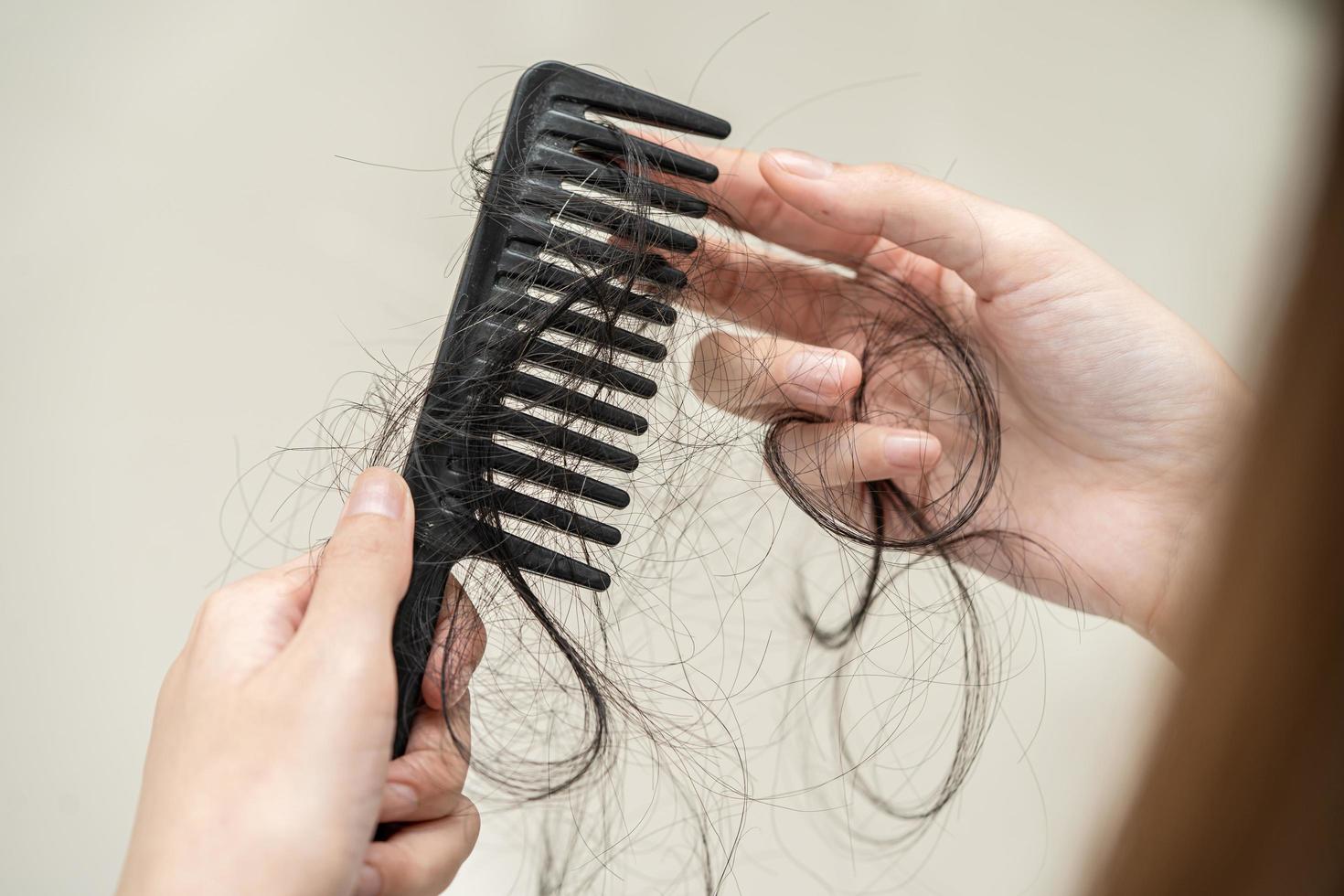 Asian woman have problem with long hair loss attach to comb brush. photo