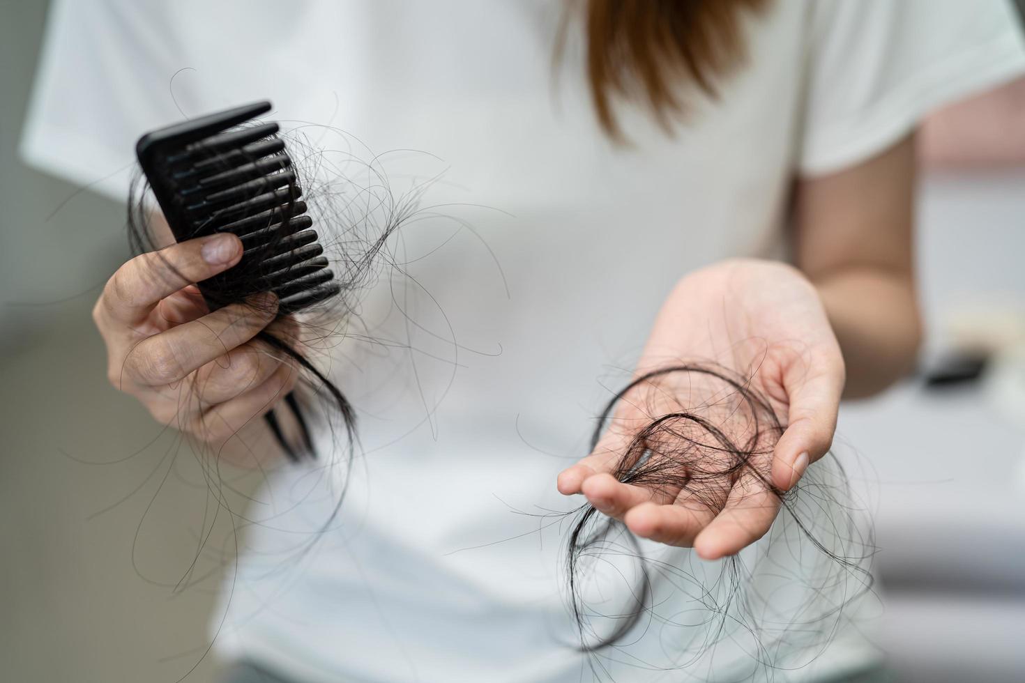 Asian woman have problem with long hair loss attach to comb brush. photo