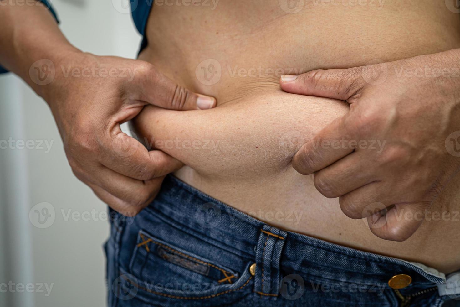 Overweight Asian woman show fat belly at office. photo