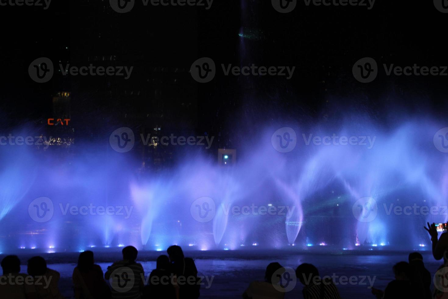 fountain or water dance show at night with colorful light with black background photo